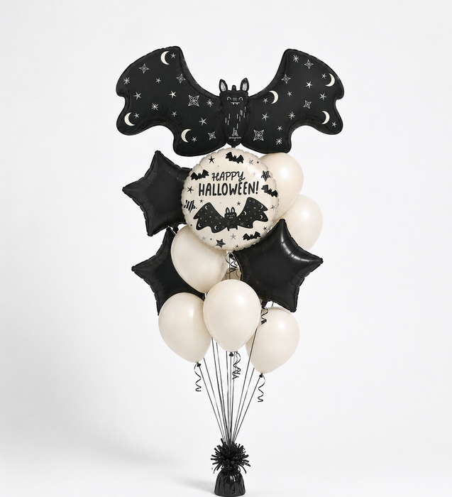 Halloween balloon bouquet with black bat-shaped foil balloons, black star balloons, cream balloons, and a round white balloon reading 'Happy Halloween!' on a black background, displayed on a white studio backdrop.
