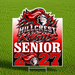 A die-cut yard sign featuring the Hillcrest Knights Senior 2027 graphic, displayed on a metal stake in a green grass field.