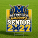A rectangular yard sign on a metal stake displayed on a green grass field. The sign features a blue and gold gradient background with a large metallic blue 'M' logo flanked by crossed arrows, the words 'MERIDIAN WARRIORS', 'SENIOR', and '2027' in bold white and gold lettering.