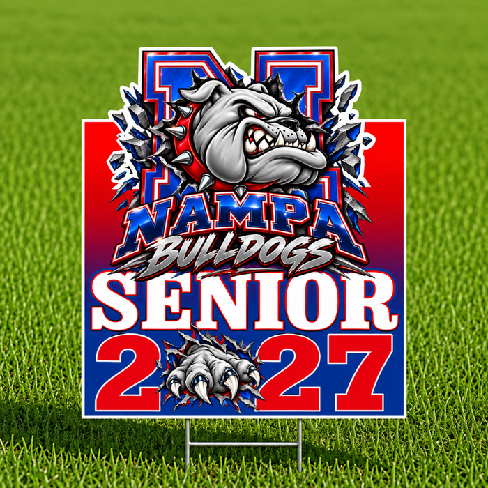 A rectangular yard sign on a metal stake displayed on a green grass field. The sign features a bulldog mascot bursting through a red, white, and blue background with the text 'NAMPA BULLDOGS SENIOR 2027'.