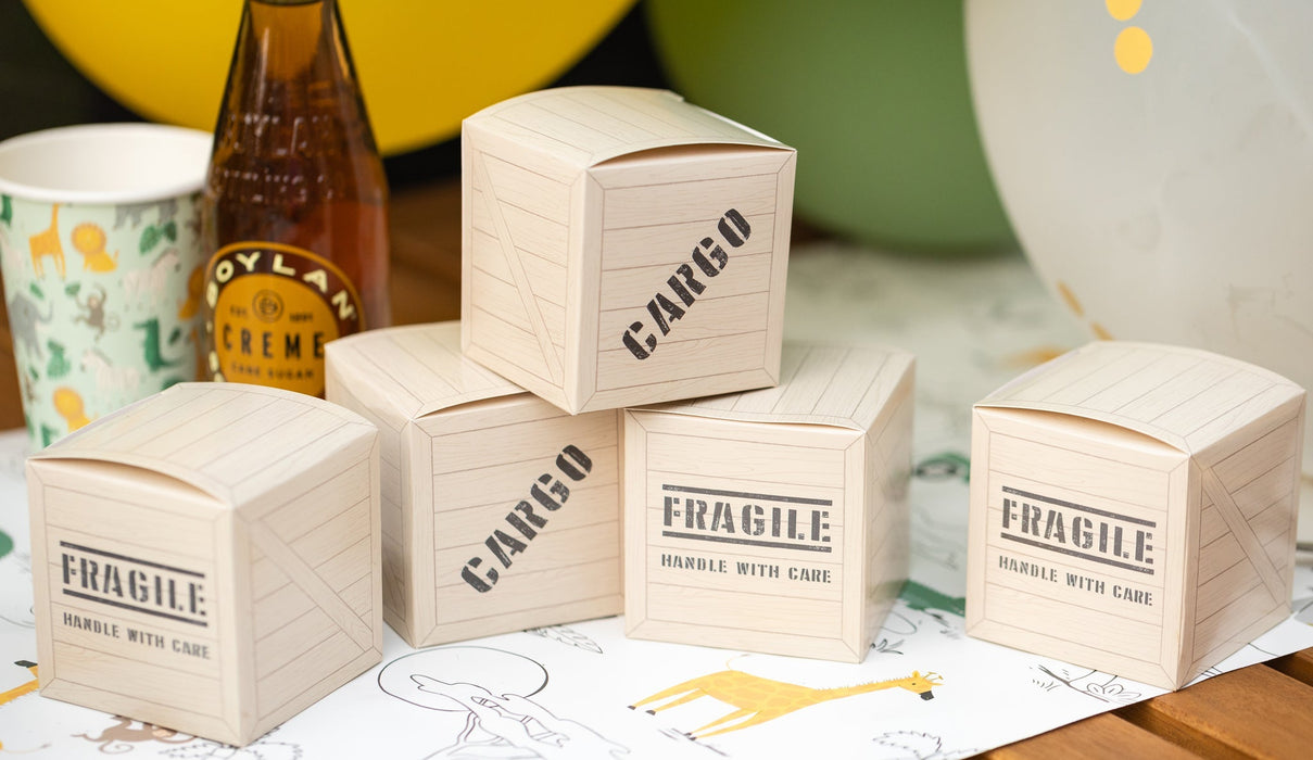Safari cargo box treat boxes designed like small wooden crates with “Cargo” and “Fragile” printed details on a party table.