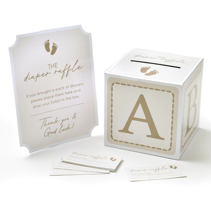 Diaper raffle game set with white and gold raffle box, matching instruction sign, and raffle tickets featuring baby footprint accents for a baby shower activity.
