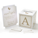 Diaper raffle game set with white and gold raffle box, matching instruction sign, and raffle tickets featuring baby footprint accents for a baby shower activity.
