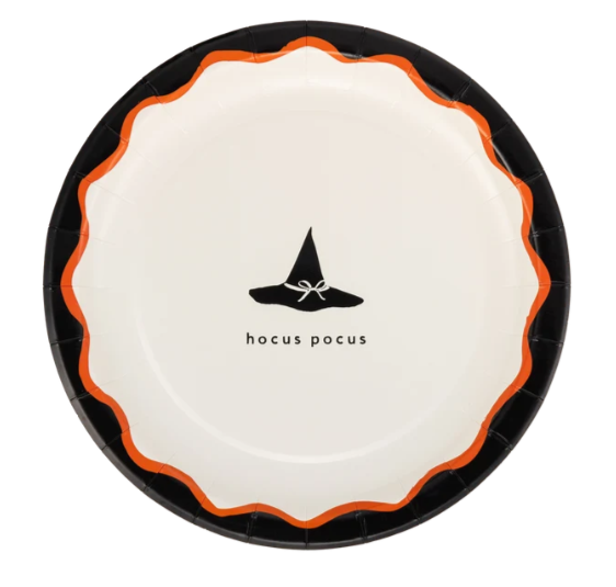 A round paper plate with a black scalloped rim, an orange inner rim, and a white center featuring a black witch hat graphic and the text 'hocus pocus'.