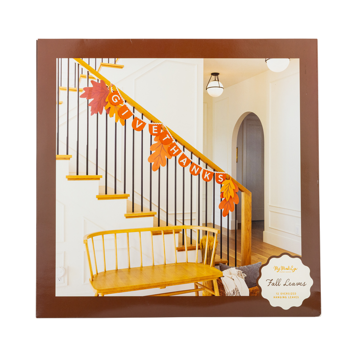 Decorative 'GIVE THANKS' banner on a staircase with fall leaves, framed by a brown border.