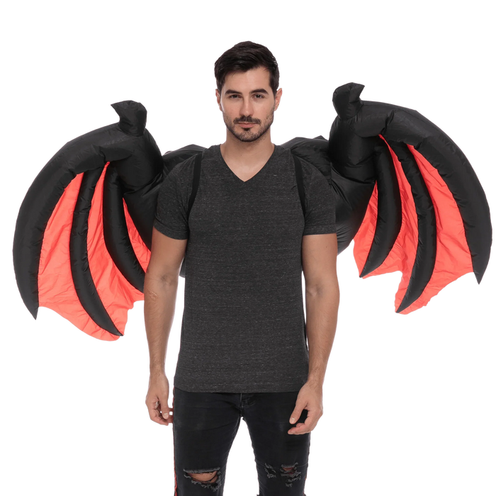 Man wearing a dark gray v-neck shirt and black distressed jeans with inflatable demon wings featuring black outer sections and bright red inner panels.