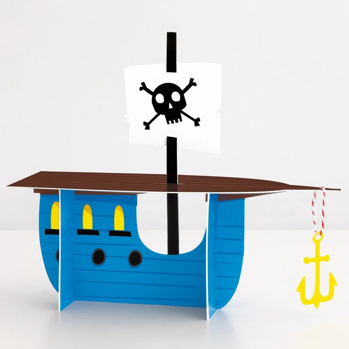 Blue cardboard pirate ship with three yellow windows, black mast with skull and crossbones flag, and yellow anchor hanging from the side.