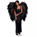 Woman wearing a black sleeveless dress with large black feathered angel wings attached at the shoulders.