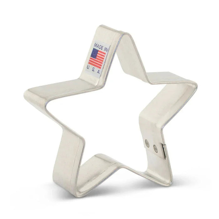Cream-colored metal star-shaped cookie cutter with a "Made in USA" label featuring an American flag on the attached fabric loop.
