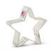 Cream-colored metal star-shaped cookie cutter with a "Made in USA" label featuring an American flag on the attached fabric loop.