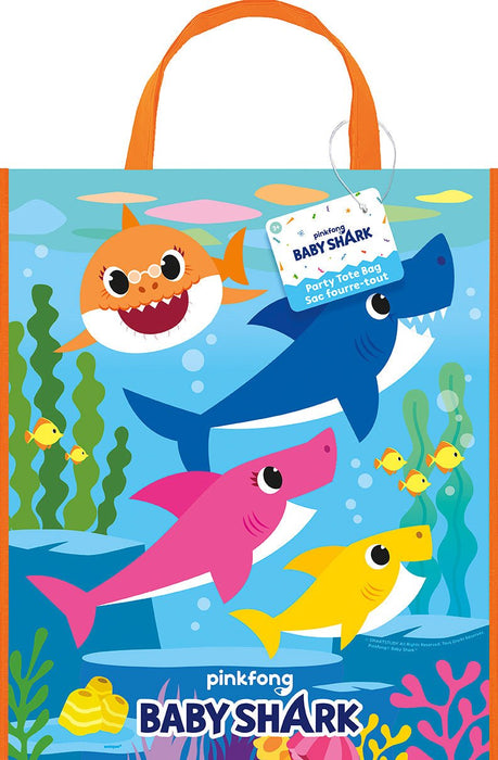 Colorful tote bag featuring cartoon sharks in orange, blue, pink, and yellow with large eyes, surrounded by underwater plants and fish on a bright blue background, with orange handles and a product tag attached.