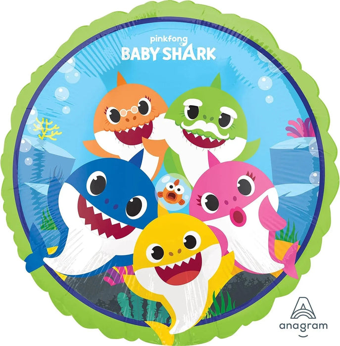 Round foil balloon featuring five colorful cartoon baby sharks in orange, blue, green, yellow, and pink with white bellies, large eyes, and open mouths, set against a light blue underwater background with seaweed and bubbles, bordered by a lime green scalloped edge.