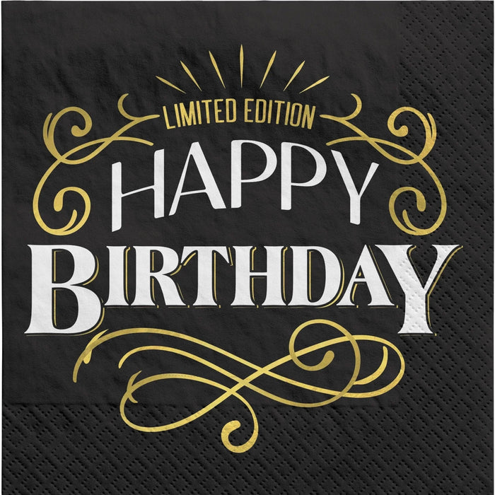Black cocktail napkin with gold and white "Limited Edition Happy Birthday" text, ornate gold scrollwork, and decorative flourishes.