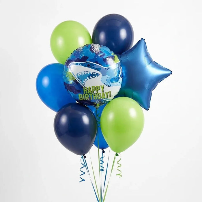 Bouquet of seven balloons in blue, green, and navy colors featuring a shark-themed foil balloon with "Happy Birthday" text in the center.