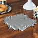 Black and white horizontally striped paper napkins displayed in a fan stack on a dark wood table next to a bagel and popcorn container.