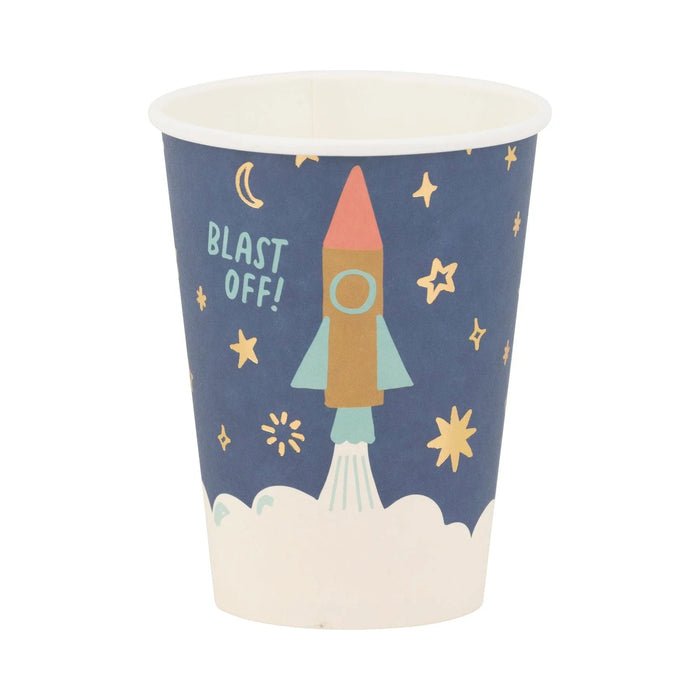 Blue disposable paper cup featuring a colorful rocket ship illustration surrounded by stars, moons, and the text "Blast Off" against a white cloud base.