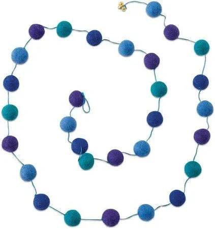 Long beaded garland with blue, teal, and purple pom poms connected by wire, arranged in a looping display.