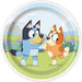 Round paper plate featuring blue and orange cartoon puppies holding flowers in a sunny garden setting with green grass and pink flowers.