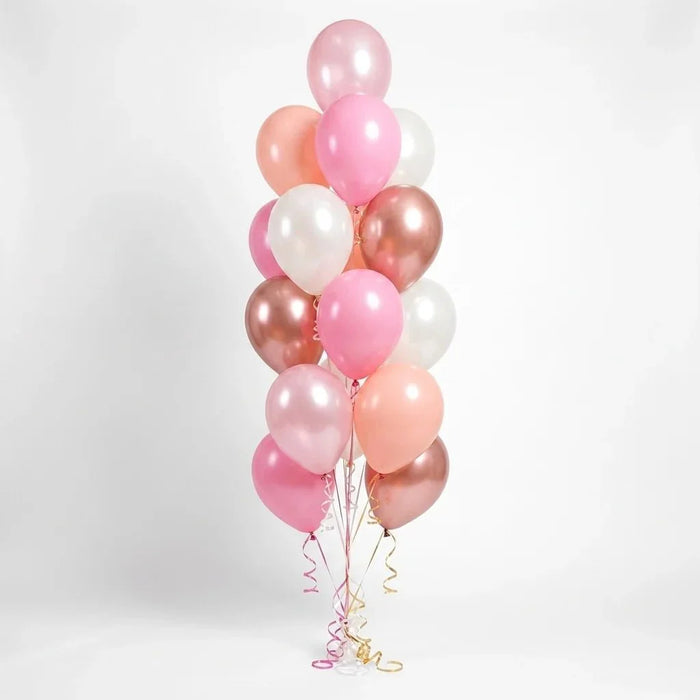 Vertical bouquet of sixteen balloons in shades of blush pink, rose gold, white, and peach with metallic finishes, gathered at the base with curled ribbon streamers.