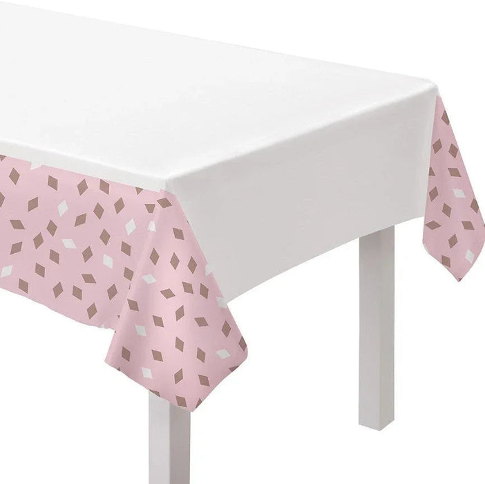 White and blush pink table cover with an all-over diamond pattern, draped across a white table.