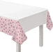 White and blush pink table cover with an all-over diamond pattern, draped across a white table.