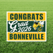 Yellow and green striped yard sign with white text reading "CONGRATS Grad 2026 BONNEVILLE" and a cartoon yellow and black hornet mascot in the center.