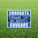 Blue and white yard sign with "CONGRATS Grad 2026 COUGARS" text and BYU logo displayed on green grass.