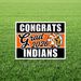 Yard sign with black and orange striped design featuring "CONGRATS Grad 2026 INDIANS" text and a Native American head logo on green grass.