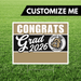 Graduation-themed sign with 'Congrats Grad 2026' text and bulldog logo on grass background