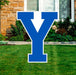 Blue and white Y-shaped yard sign displayed on a residential lawn with stone house and landscaping in the background.