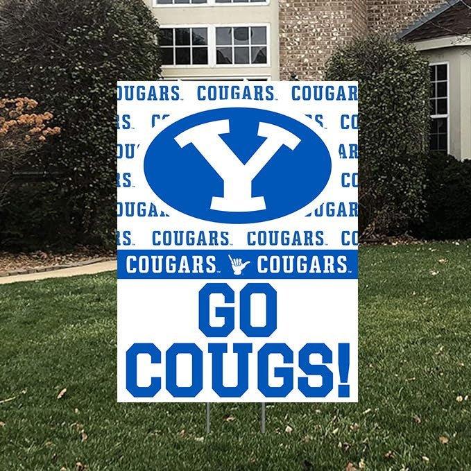 Blue and white BYU Cougars yard sign featuring a large Y logo, repeated text, and "GO COUGS!" displayed on grass in front of a building.