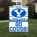 Blue and white BYU Cougars yard sign featuring a large Y logo, repeated text, and "GO COUGS!" displayed on grass in front of a building.