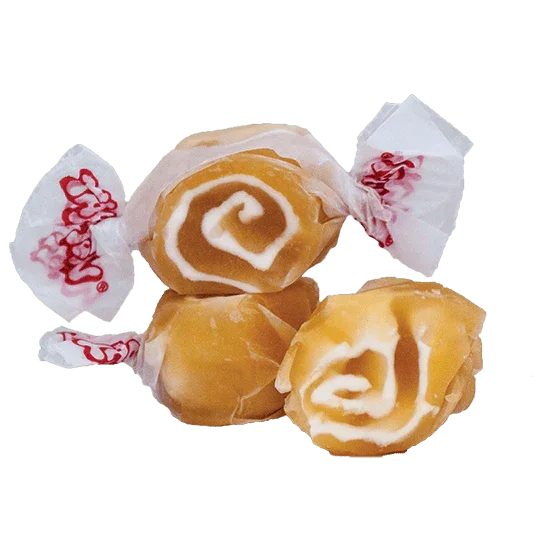 Four golden brown taffy candies with white caramel swirl designs wrapped in white and red paper packaging arranged on a white background.