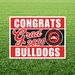 Graduation-themed sign with 'Congrats Grad 2026 Bulldogs' on a grass background