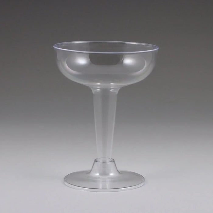Clear plastic champagne coupe glass with a wide bowl, tall stem, and broad base, shown against a neutral gray background.