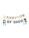 Gold and navy letter banner reading "CHAMPION OF DADS" with two small gold trophy cups hanging from teal ribbons on either side.