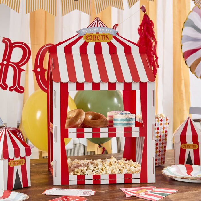 Red and white striped cardboard circus tent with "Welcome to the Circus" banner, displaying donuts, layered cake, and popcorn in window compartments.