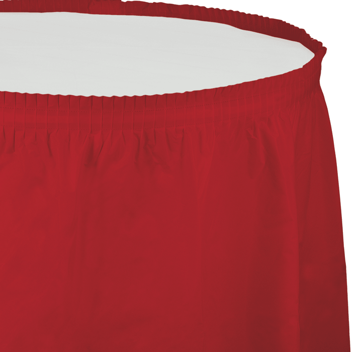 Red plastic tableskirt with elastic waistband and vertical pleating, shown fully extended against a white background.