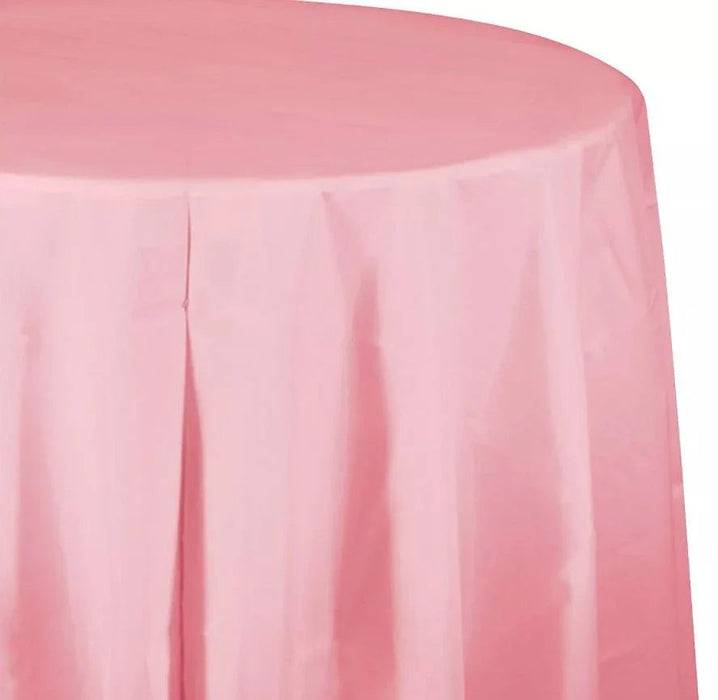 Pink round plastic tablecloth with vertical pleats and draping, shown covering a round table surface.