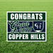 Green and navy yard sign with white text reading "Congrats Grad 2026" and "Copper Hills" with a shield logo, displayed on grass.