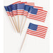 Six small American flags with blue canton sections, red and white stripes, and wooden picks arranged in a fan display on white background.