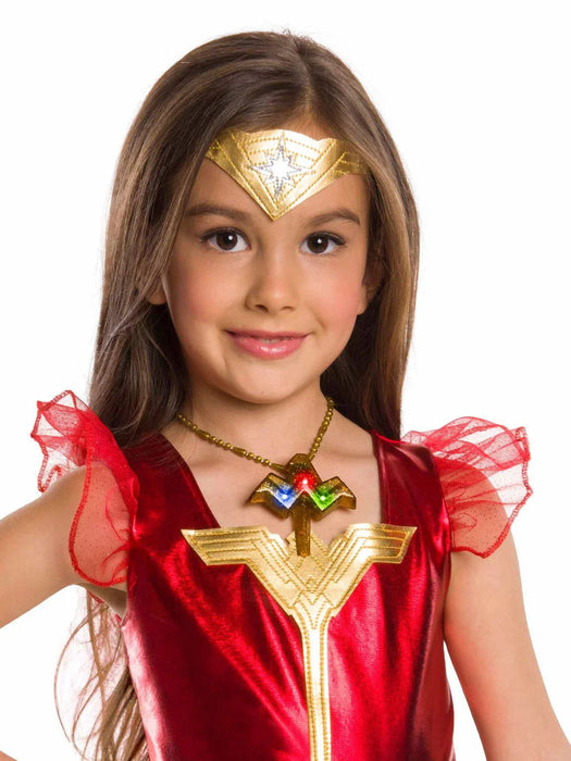 Child wearing a red and gold Wonder Woman costume with a gold tiara featuring a white star, red tulle shoulder ruffles, and a light-up necklace with a gold emblem and colored gems.