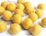 Approximately twenty golden yellow fuzzy pompom balls arranged on a white surface.