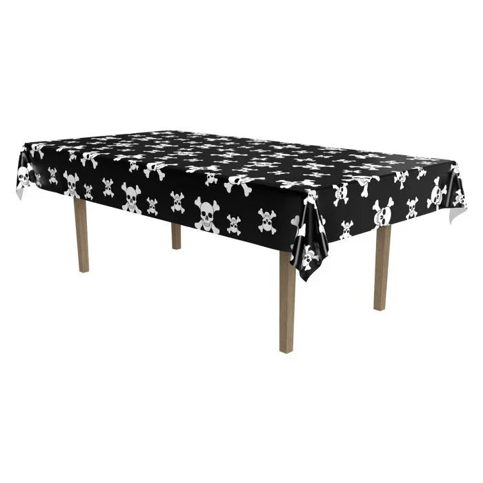 Black rectangular tablecloth with white skull and crossbones pattern, draped over a wooden table with four tan legs.