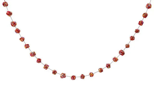 Red and pink glittered wool ball garland with connected spheres draped in a festive swag against a white background.
