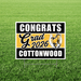 Cottonwood High School graduation yard sign featuring black and gold stripes with a bucking horse logo, reading "Congrats Grad 2026 Cottonwood" on green grass.