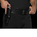 Black leather single gun holster with belt attachment, displayed worn at waist level with hands adjusting the belt strap.