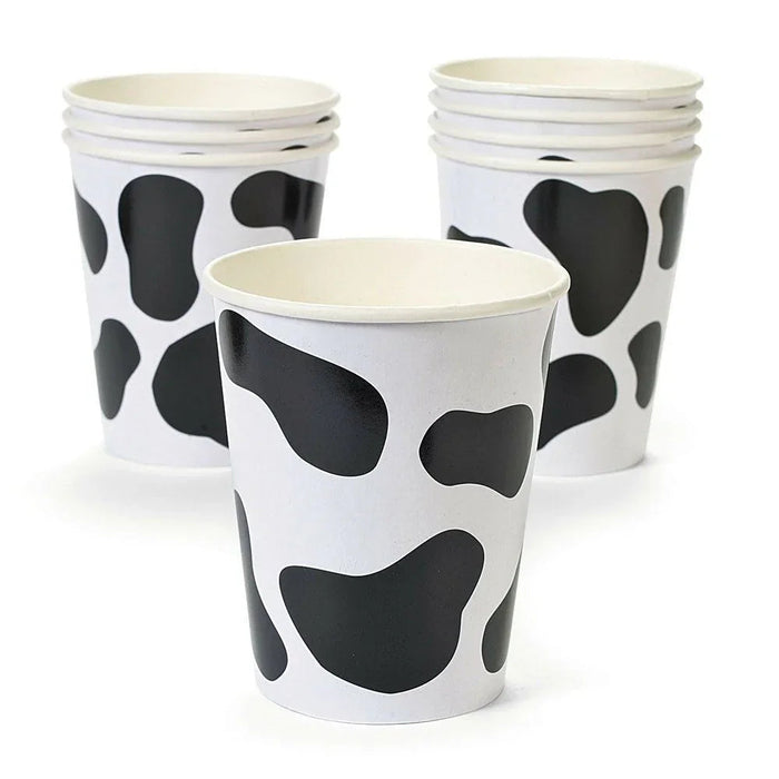 Three white paper cups with black cow spot patterns arranged in a triangular display against a white background.