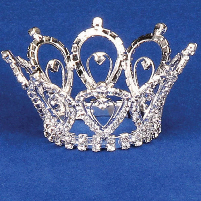 Ornate silver-toned crystal crown tiara with five peaks, decorative heart centerpiece, and rhinestone embellishments throughout, displayed against a blue background.