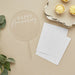 Clear acrylic round cake topper with "HAPPY Anniversary" in white script text on a stick, displayed with blank white cards, potted succulent, and yellow frosted cupcakes on a beige background.